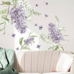 a white couch sitting next to a wall with purple flowers on it