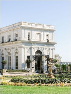 a large white building with a fountain in front of it and lots of greenery