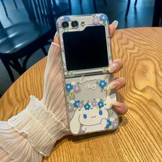 a woman's hand holding up a cell phone with an image of a unicorn on it