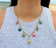 Get ready for summer with this Cute Seaside Charm Necklace, a whimsical blend of color and coastal vibes that's perfect for the season. This playful necklace features an array of colorful charms, ideal for those long, sun-soaked days. At its heart lies a beautiful gold conch shell charm, surrounded by adorable shell charms and cute starfish charms. Each charm is a tiny piece of the beach that is the perfect addition to any outfit.  Handmade and bursting with charm, this necklace is the perfect a Shell Charm Necklace, Beach Necklace, Necklace Colorful, Coastal Vibes, Beach Necklaces, Hippie Necklace, Conch Shell, Colourful Necklace, Fun Summer