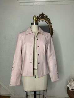 90's vintage pink button up leather jacket with floral cut away design at the bottom of the sleeves. This little number is adorable, there was light wear if any to this jacket. This is a light jacket, and the leather is relatively on the thinner side. Size 4   Size S Lount Pink Retro Velvet Jacket, Spring Leather Jacket With Snap Buttons, Fitted Leather Jacket With Buttons For Spring, Spring Single-breasted Leather Jacket With Long Sleeves, Spring Fitted Outerwear With Button Closure, Single-breasted Long-sleeve Leather Jacket For Spring, Fitted Outerwear With Button Closure For Spring, Fitted Spring Outerwear With Button Closure, Spring Long Sleeve Pink Leather Jacket