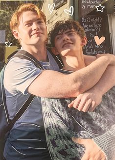 two young men hugging each other in front of a store window with writing on it