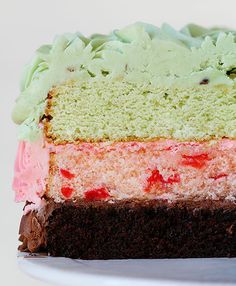 a slice of cake on a white plate with green frosting and pink icing