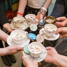 a group of people holding tea cups and saucers