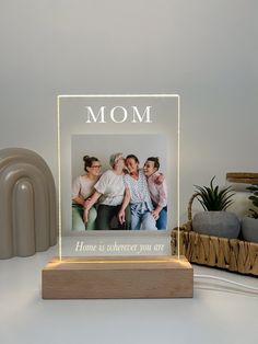 a light up photo frame sitting on top of a table next to a plant and vase