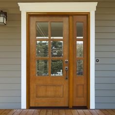 a wooden door with two sidelights on the outside of a gray house and wood flooring