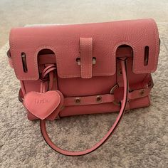 a pink handbag sitting on top of a carpet