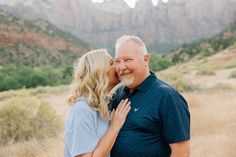 an older couple kissing in front of mountains