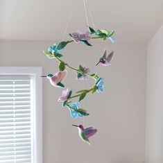 a wind chime hanging from the ceiling in a room with white walls and windows