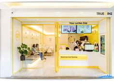 the inside of a salon with yellow trimming and white walls, two women sitting in chairs