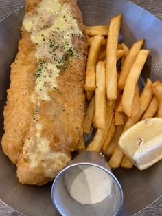 fish and fries are served in a bowl with a side of dipping sauce on the side