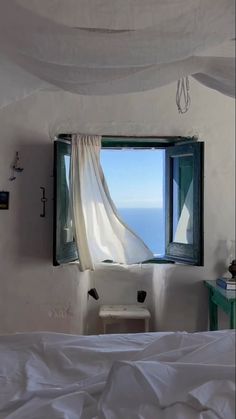 an open window in a bedroom overlooking the ocean