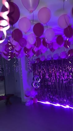 purple balloons and streamers are hanging from the ceiling