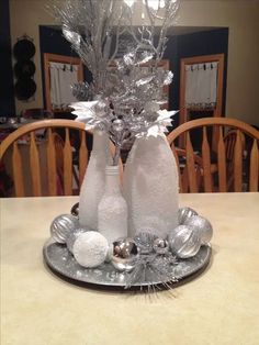 two wine bottles sitting on top of a silver plate covered in tinsel and snow