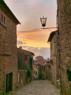 an alley way with cobblestone stone buildings and a street lamp in the distance