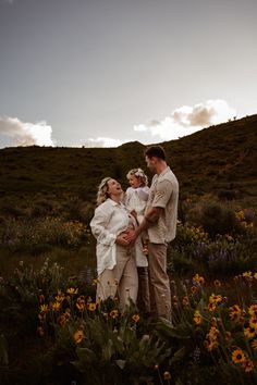 three people standing in a field full of flowers