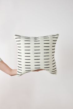 a person holding a black and white pillow in the air with their hand on it