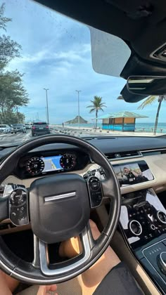 a man driving a car on the beach with his hands on the steering wheel and dashboard