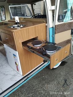 a camper van with its door open and two burners on the stove