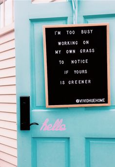 a blue door with a sign on it that says i'm too busy working on my own grass to notice if your is greener