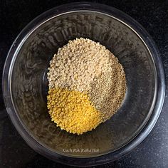 a bowl filled with grains and seasoning sitting on top of a black countertop