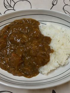 a white plate topped with rice and meat covered in gravy on top of a table