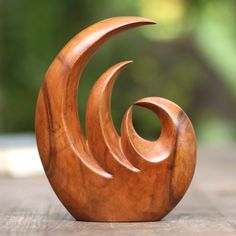 a wooden sculpture sitting on top of a wooden table next to a green tree in the background