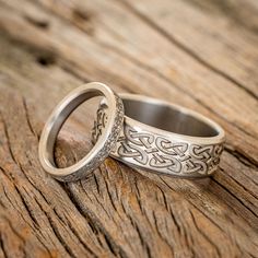 two wedding rings sitting on top of a wooden table next to each other with intricate designs