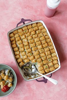 a casserole dish with tater tots next to a bowl of salad