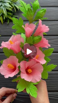 someone is holding some pink flowers with green leaves in their hand and the video shows how to make them look like they are blooming