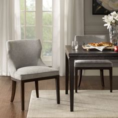 a dining room table with two chairs and a vase filled with flowers on top of it