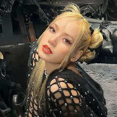 a woman with blonde hair and red lipstick posing for a photo in front of a car