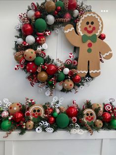 a wreath decorated with gingerbreads, candy canes and christmas ornaments is hanging on the wall