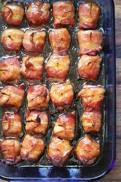 bacon wrapped chicken bites are in a blue casserole dish on a wooden table