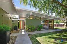 a house that has some plants in the front yard and trees on the side of it