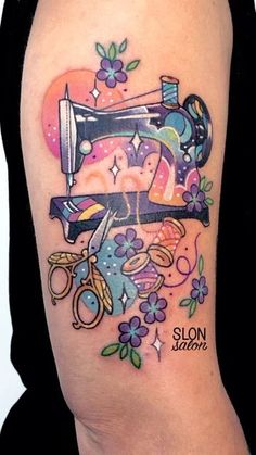 a woman's arm with a tattoo on it that has scissors, flowers and a sewing machine