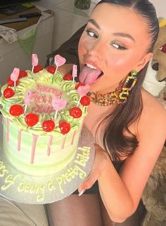 a woman sticking her tongue out while holding a cake