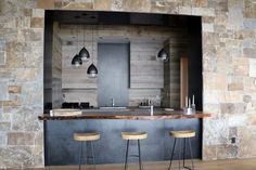 an open kitchen area with bar stools and stone wall in the backround