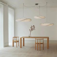 a dining table with four chairs and three lights hanging from it's ceiling above