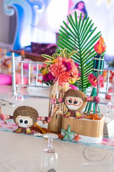 a table topped with dolls and flowers on top of a white table covered in colorful decorations