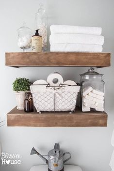 two wooden shelves above a toilet with towels and other items on top of the shelf