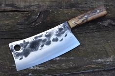 a large knife sitting on top of a wooden table next to a piece of wood