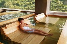 a young boy laying on top of a wooden floor next to a swimming pool in a house