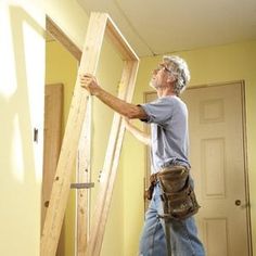 a man standing in front of a ladder holding up wood planks to the ceiling