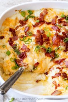 a close up of a casserole dish with cheese and bacon on it, topped with green onions