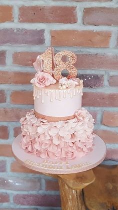 a three tiered cake with pink flowers and the number twenty on top is sitting on a wooden stand