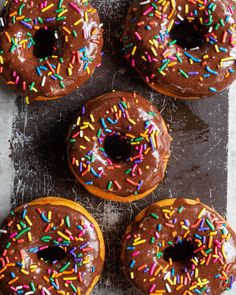 four chocolate donuts with sprinkles on top