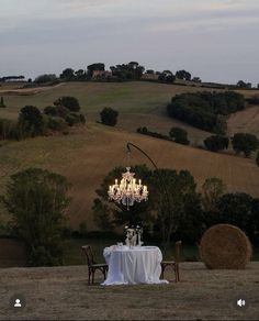 a chandelier hanging over a table in the middle of a field