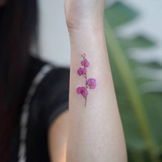 a small pink flower tattoo on the wrist