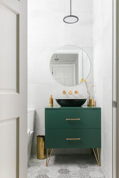 a bathroom with a sink, mirror and green cabinet in the middle of the room